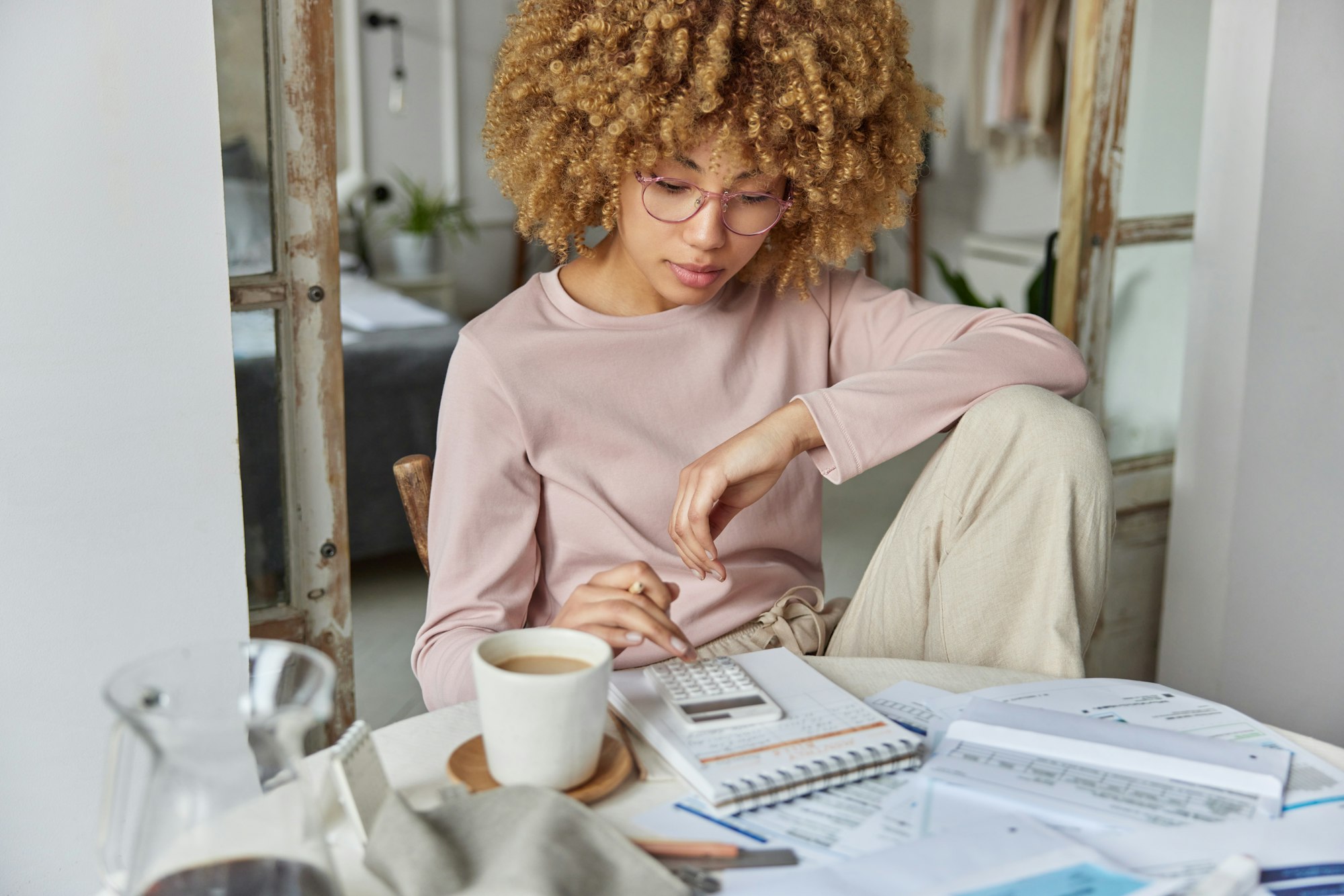 Serious curly haired woman manages household family budget calculates expenditures takes care of Serious curly haired woman manages household family budget calculates expenditures takes care of
